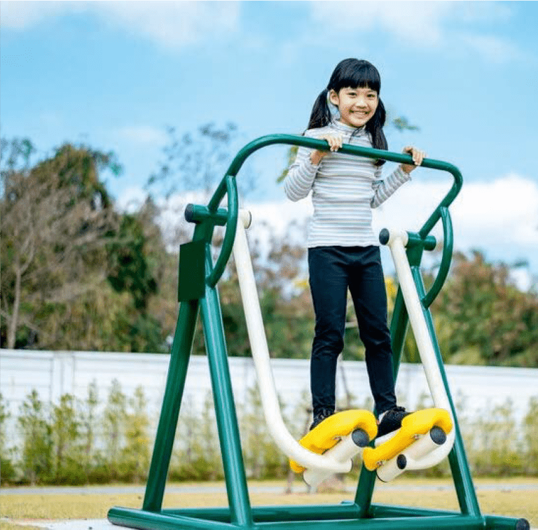 Child on outdoor elliptical trainer in a park.