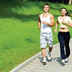 Two people jogging on a park path surrounded by greenery.